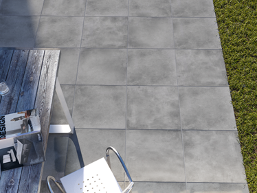 Ansicht Terrasse mit Betonoptikplatten Ombra, Rasenanschnitt und Outdoormöbeln