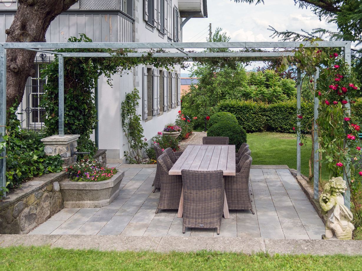 Sandsteinplatte Kandla Grey auf einer Terrasse mit Pergola und angrenzendem Rasen