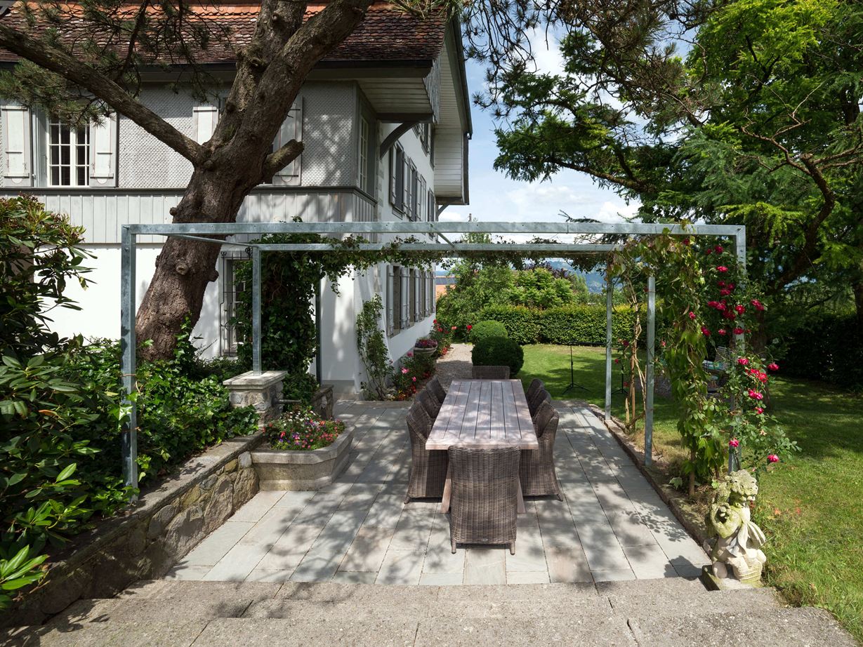 Terrasse mit Natursteinplatten aus grauem Sandstein in natürlichem Garten