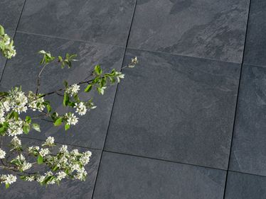 Dunkle Schieferoptikplatten Alpine Black mit Zweig im Vordergrund