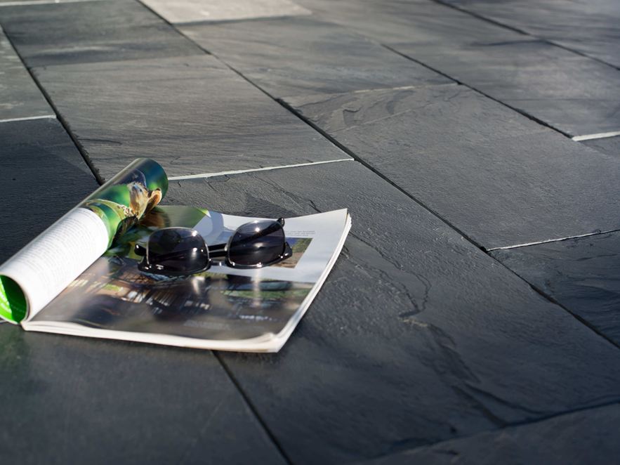 Eine Zeitschrift und eine Sonnenbrille auf Schieferplatten in der Sonne