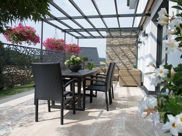 Terrasse mit dunklen Gartenmöbeln und holzähnlichem Travertin Natura als Bodenbelag