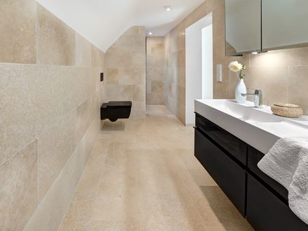 Badezimmer mit modernen Möbeln und Kalksteinfliesen Cleopatra Light auf dem Boden und an der Wand