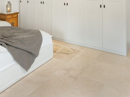 Schlafzimmer mit weißem Schrank und weißem Bett, auf dem Boden Kalksteinfliesen in Beige