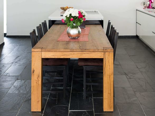 Esstisch aus Holz in Kombination mit dunklem Schieferboden und weissen Wänden