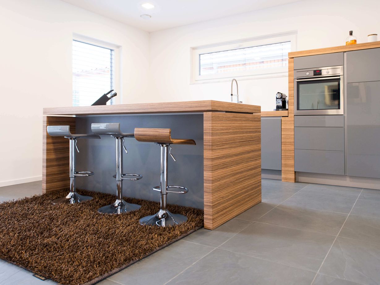 Küche mit freier Bartheke, modernen Holzelementen und dunklem Schiefer als Bodenbelag
