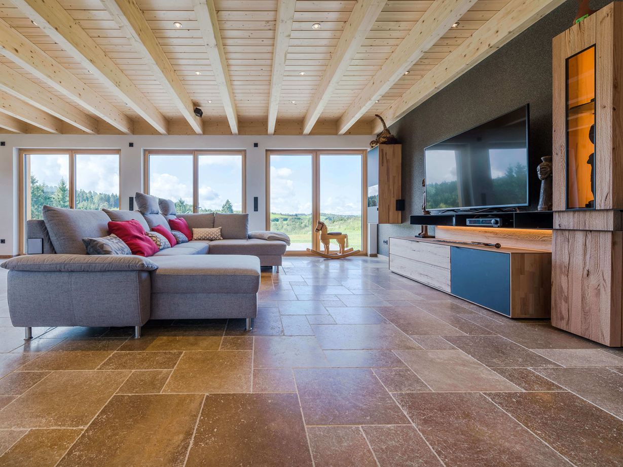Wohnzimmer mit grauem Sofa und walnussbraunen Travertinfliesen Noce SELECT