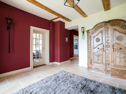 Eingangsbereich mit Holzschrank, einer roten Wand und beigen Travertinfliesen