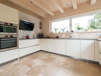 Küche mit weissen Möbeln und beigefarbener Travertinfliese Rustic als Bodenbelag