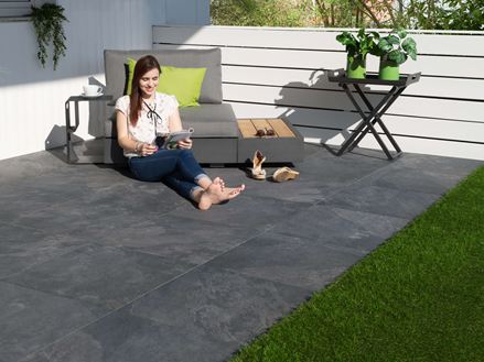 Frau sitzt auf Terrassenplatten Alpine Black