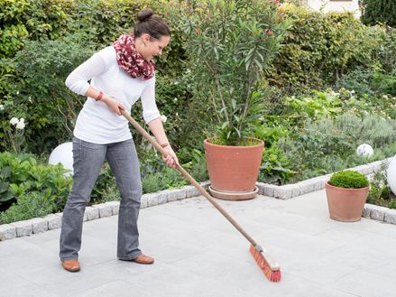 Frau reinigt Granit Mundo Grau-Terrasse