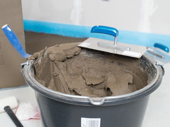 Ein Eimer mit Natursteinkleber und Zahntraufel