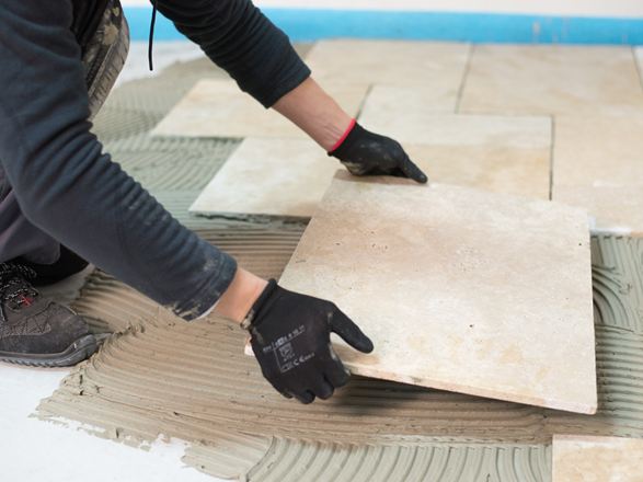 Travertinfliese wird ins Kleberbett gelegt